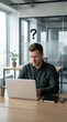 © Furkan - Confused Businessman Working on Laptop with Question Mark Above Head in Office, Problem Solving Concept, Business Challenge, Decision Making, Workplace Stress, Vertical bg