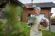 © Halfpoint - Senior woman gardening in spring, holding flowering plants.
