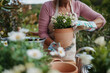 © Halfpoint - Senior woman caring for flower plants in spring garden.