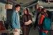 © Zamrznuti tonovi - Diverse students talking with a smiling female teacher and older mentor, discussing academic support in a modern university setting