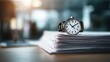 © Never - A wristwatch rests atop a stack of papers in a blurred office setting