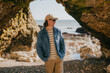 © Reuben - Man stands beneath rocky archway, gazing out to sea