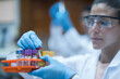 © .shock - Young laboratory technician handling blood test tubes with gloves and goggles in clinical diagnostic lab
