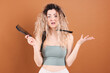 © New Africa - Unhappy woman trying to brush her tangled hair on brown background