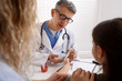 © New Africa - Endocrinologist in glasses checking little girl's blood sugar level with lancet pen while her mother supporting her at white desk in clinic, selective focus
