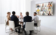 © New Africa - Team of office employees having video chat with remote coworkers in meeting room