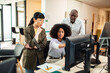 © Marko Geber - Diverse coworkers collaborating at desktop computers in modern office
