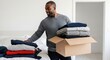 © Running opossum - young man organizing clothes in a box in bedroom during move, smiling and enjoying the process