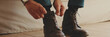 © Andrii Nekrasov - Close-up of legs of mature man putting on casual boots, tying shoelaces. Panoramic