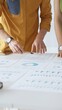 © rogerphoto - Business professionals analyzing financial reports, pointing at data points on charts and graphs lying across white desk surface