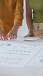 © rogerphoto - Business professionals reviewing financial charts, calculating data with calculator on table, analyzing statistics during collaborative project meeting.