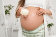 © Pixel-Shot - Young pregnant woman applying cream on her tummy in bathroom, closeup