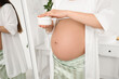 © Pixel-Shot - Young pregnant woman with jar of cream in bathroom, closeup