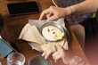 © Semiglass - Small plate with flatbread, creamy dip, and cucumber slices sits on wooden table alongside phone, water glass, and hands in relaxed dining setting. Scene conveys informal atmosphere, texture, and ever