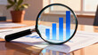 © Mamer - Close-up view of a magnifying glass over a bar chart, illustrating financial growth and analysis