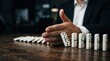 © Masque - Manager's hand stopping domino effect on wooden surface for risk management and prevention.