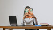 © Lustre Art Group  - Young woman sitting at desk holding printed smiling face panel office lifestyle portrait. Concept of workplace emotions, professional image, mood masking, communication and corporate identity.