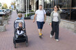 © Anna - Parents with two children are strolling down a city street. The son is pushing a stroller with an adorable baby in it. Family, lifestyle, everyday life