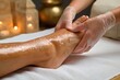 © whitestorm - Close-up of a spa professional giving a relaxing foot massage with oil and scrub on a white towel.