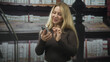 © Krakenimages.com - Woman holding smartphone, tapping screen while smiling amid tall shelves of bound books in a library building; casual happiness.