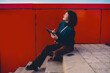© BullRun - Young woman sits on concrete steps holding a tablet and stylus, smiling up while drawing and gesturing, capturing mobile creativity, digital ideation and tech‑enabled artistic expression.