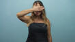 © Krakenimages.com - Woman wearing strapless denim dress smiling with hand covering eyes and exposed forearm in studio, eyeglasses visible in other frames; playful shyness.