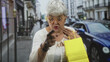 © Krakenimages.com - Woman holding yellow shopping bag pointing with hand on street while speaking; surprise accusation conflict.