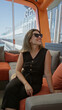 © Krakenimages.com - Woman wearing sunglasses with hand behind head sitting on orange sofa on the cruise terrace building; vacation calm.