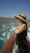 © Krakenimages.com - Woman rests bare arms on wooden rail of cruise deck, wearing straw sunhat and sunglasses while smiling toward sea; serenity travel vacation.