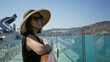 © Krakenimages.com - Woman leaning on ship rail with bare shoulder visible, smiling while wearing sunhat and sunglasses on building deck walkway under clear blue sky; serenity vacation leisure.