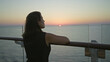 © Krakenimages.com - Woman leans with bare arm on cruise ship deck rail looking at sunset over ocean, profile view at dusk; serenity.