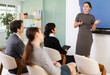 © JackF - Young woman gives presentation to colleagues in office conference room using wireless remote control