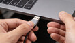 © Nattapol - Focused male adult hand carefully plugging USB cable into grey laptop port, establishing vital digital connection for data transfer or device