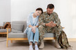 © eakgrungenerd - Sad military couple sitting on sofa, soldier in uniform and wife showing emotional stress, relationship problem, mental health and support concept after returning from service.
