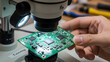 © Malik - Technician inspecting a printed circuit board under a laboratory microscope.