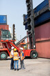 © NVB Stocker - Hispanic man harbor worker talking on the walkie-talkie radio and control loading containers at container warehouse. container yard port of import and export goods