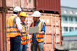 © NVB Stocker - Hispanic man harbor worker talking on the walkie-talkie radio and control loading containers at container warehouse. container yard port of import and export goods