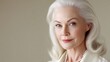 © buraratn - Elegant older woman with silver hair and pearls exhibiting confidence and beauty in a soft, neutral-tone environment, embodying grace and sophistication