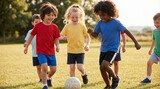 Group of children playing soccer on grassy field in sunlight  