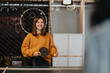© qunica.com - A smiling young woman plays table tennis holding a paddle and ball. She enjoys a casual indoor game while a friend watches nearby.