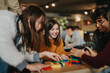© qunica.com - A group of students and friends play with colorful wooden blocks and smile together. The casual indoor scene shows young adults enjoying a cooperative tabletop game and social time.