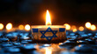 © Hanna - Candle with Israeli flag design burns among small candles on a dark surface with water droplets