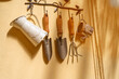 © Anna - Miniature gardening equipment including a rake and trowels hanging on a rustic hook.