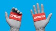 © Aether Io - Two gloved hands hold red cards with the words EXPANSION and CONTRACTION written in white text presented against a vibrant blue backdrop illustrating opposing concepts business