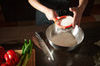 © Taras Grebinets - Hands Sifting Flour Into Mixing Bowl on Kitchen Counter With Knife and Fresh Vegetables