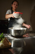 © Taras Grebinets - Woman Sifting Flour Into Mixing Bowl While Baking In Kitchen