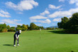 © khmelev - Man putting golf ball on green golf course.