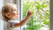© Norfarizan - Baby looking at spring blossoms through a window