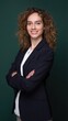 © Arnab Dey - Confident professional woman bank employee in black blazer standing with arms crossed against green background with copy space.
