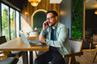 © djile - Man talking on smartphone while working remotely in cafe